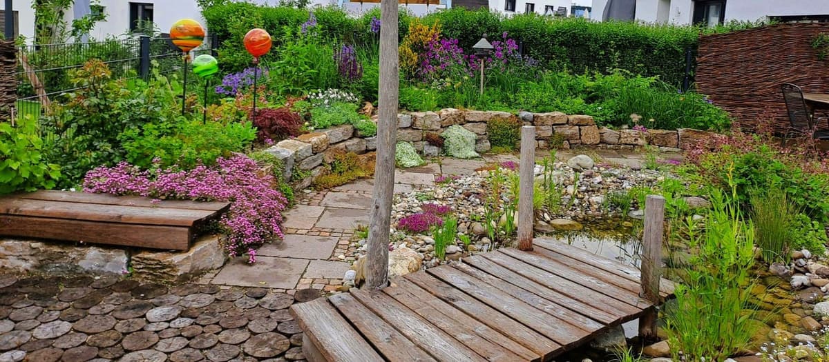 Fertig angelegter Naturteich mit Holzsteg und üppiger Bepflanzung